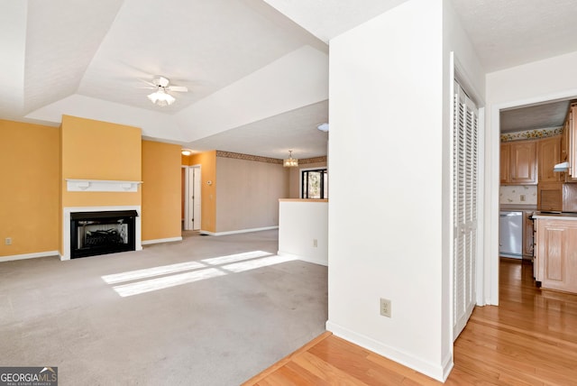 unfurnished living room featuring light hardwood / wood-style floors, ceiling fan, and a tray ceiling