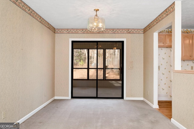 spare room featuring a chandelier and light carpet