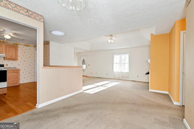 unfurnished living room featuring ceiling fan, light carpet, and a textured ceiling