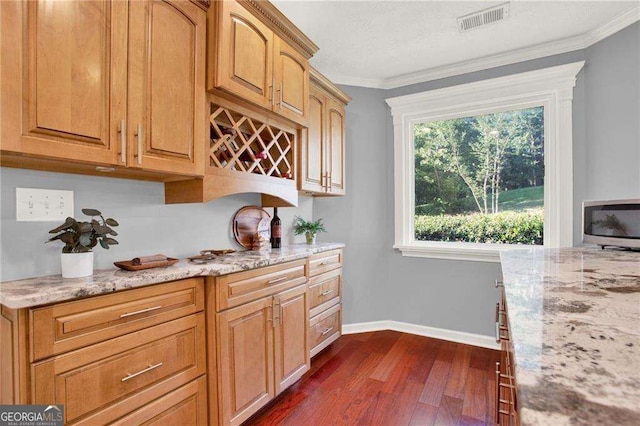 kitchen with dark hardwood / wood-style flooring, crown molding, and light stone countertops