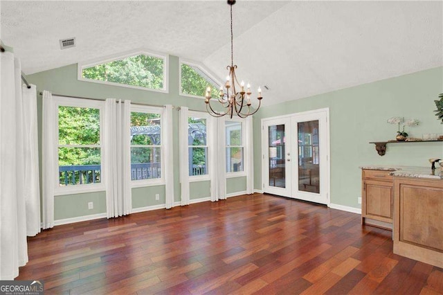 unfurnished dining area with a textured ceiling, vaulted ceiling, french doors, dark hardwood / wood-style flooring, and a notable chandelier