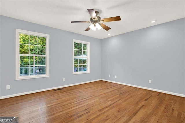 empty room with wood-type flooring, ceiling fan, and a healthy amount of sunlight