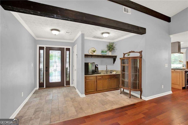 entrance foyer featuring a textured ceiling, hardwood / wood-style floors, and crown molding