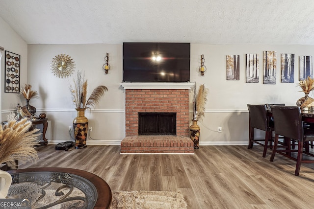 living room with a textured ceiling, a brick fireplace, and hardwood / wood-style flooring