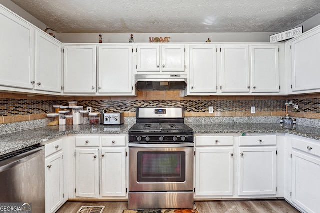 kitchen with a textured ceiling, stainless steel appliances, tasteful backsplash, white cabinetry, and dark stone countertops