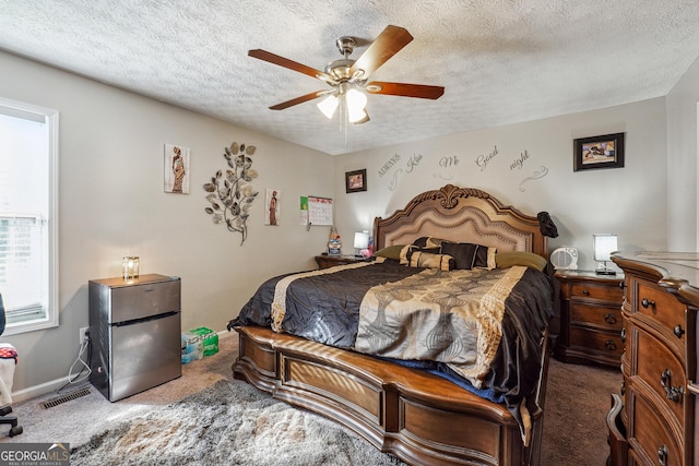 carpeted bedroom with a textured ceiling, ceiling fan, and stainless steel fridge