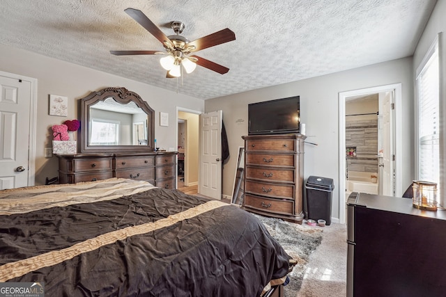 carpeted bedroom with ceiling fan, connected bathroom, a textured ceiling, and stainless steel refrigerator