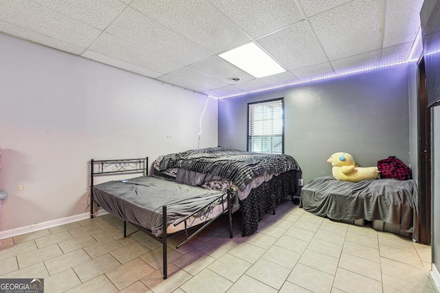 bedroom featuring a paneled ceiling and light tile patterned floors