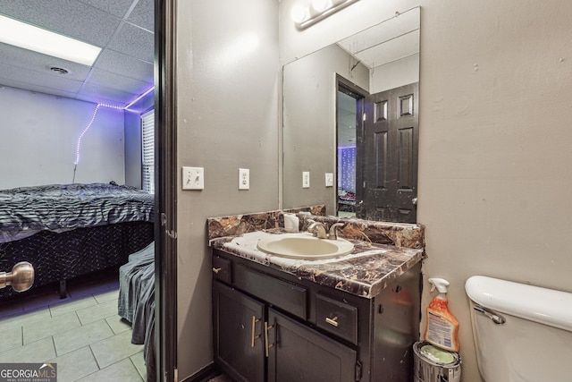 bathroom featuring toilet, a drop ceiling, tile patterned floors, and vanity