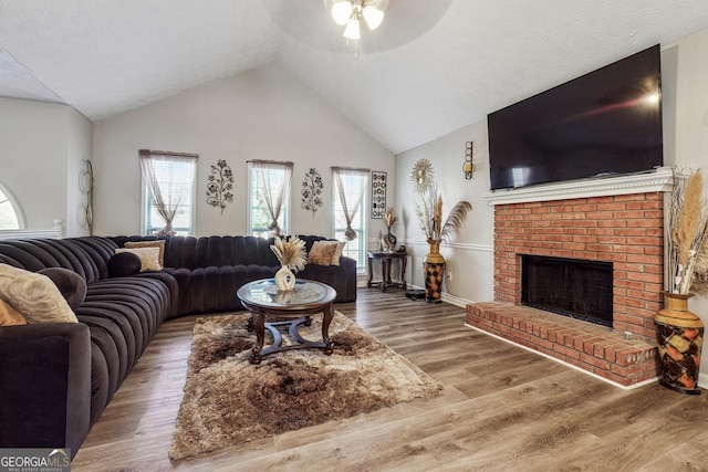 living room with vaulted ceiling, a fireplace, ceiling fan, and hardwood / wood-style flooring