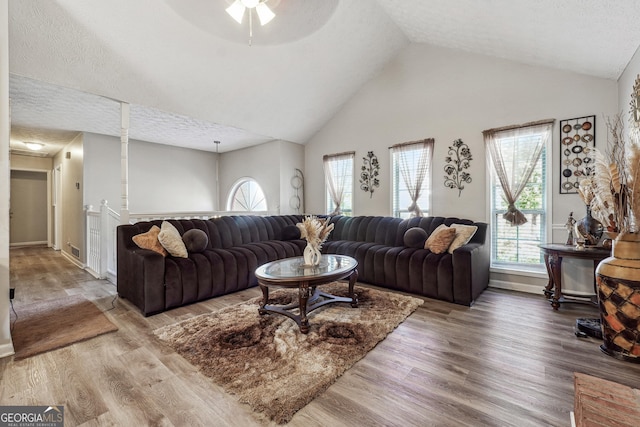 living room with wood-type flooring, high vaulted ceiling, a textured ceiling, and ceiling fan