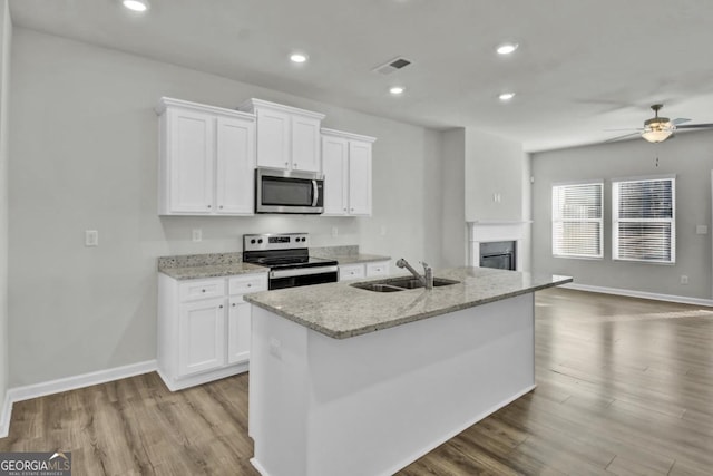 kitchen with stainless steel appliances, a kitchen island with sink, white cabinetry, ceiling fan, and sink