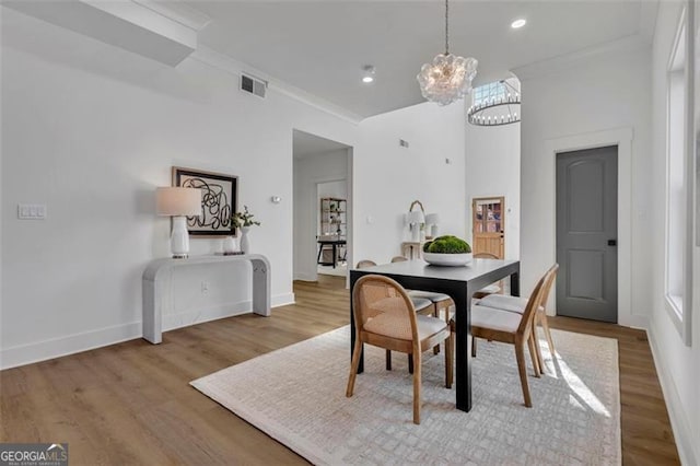 dining room featuring ornamental molding, a chandelier, and light hardwood / wood-style flooring