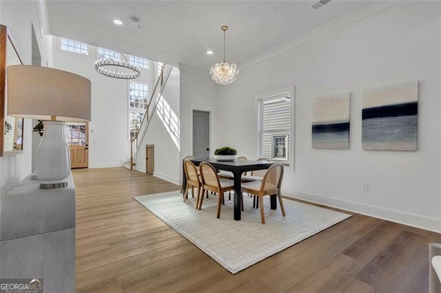 dining space featuring wood-type flooring, crown molding, and an inviting chandelier