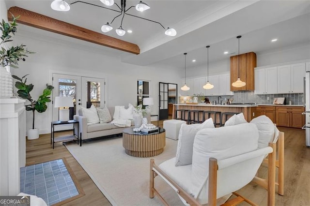 living room with a chandelier, beam ceiling, french doors, and light wood-type flooring