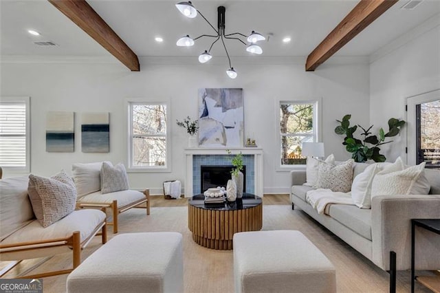 living room featuring light hardwood / wood-style floors, beam ceiling, an inviting chandelier, a tiled fireplace, and plenty of natural light