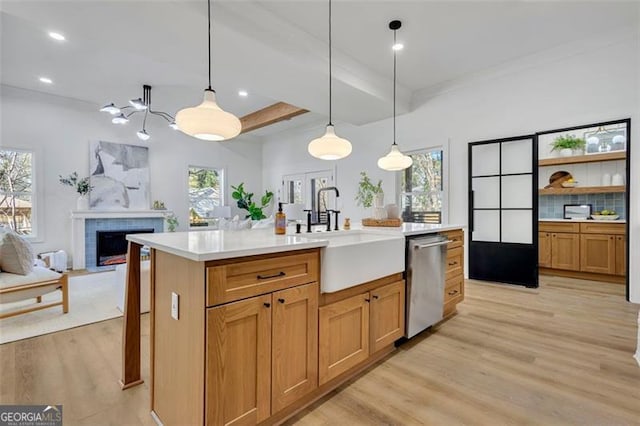 kitchen featuring light hardwood / wood-style floors, dishwasher, sink, decorative light fixtures, and an island with sink