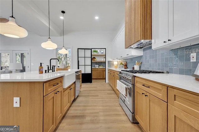 kitchen featuring pendant lighting, white cabinetry, exhaust hood, and appliances with stainless steel finishes