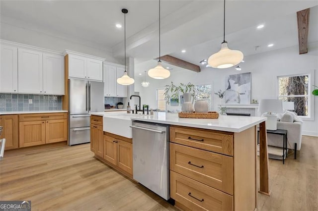 kitchen featuring pendant lighting, a center island with sink, appliances with stainless steel finishes, and decorative backsplash