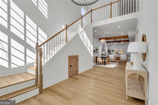 entrance foyer featuring hardwood / wood-style flooring, a chandelier, a high ceiling, and beamed ceiling