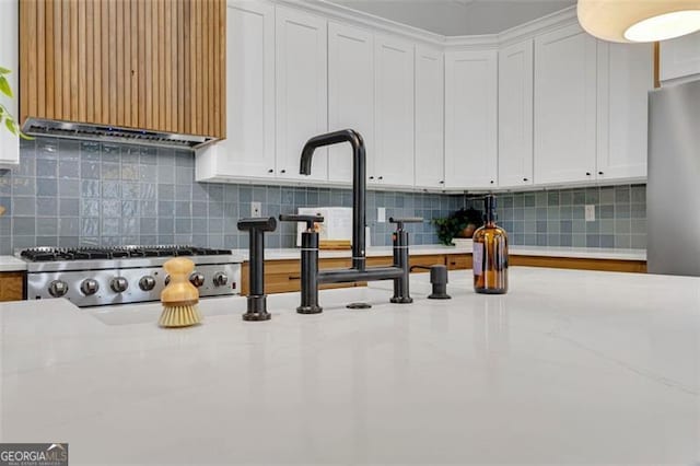 kitchen featuring white cabinets, light stone countertops, and decorative backsplash