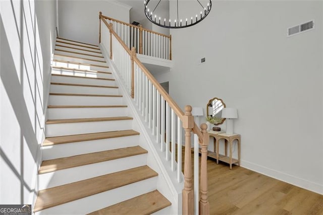 stairway featuring hardwood / wood-style flooring and a notable chandelier