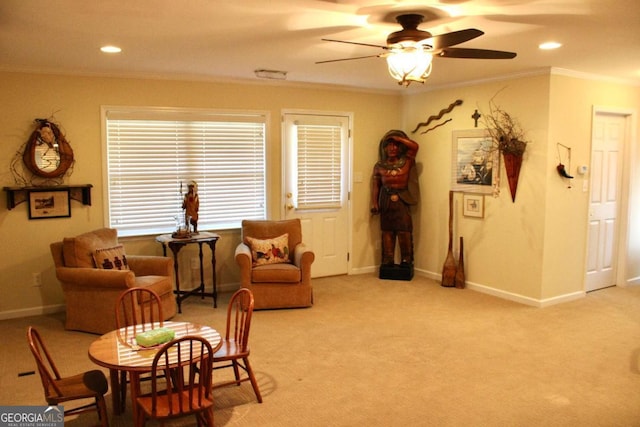 living area with light colored carpet, ceiling fan, and ornamental molding