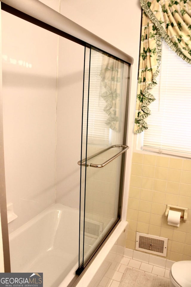 bathroom featuring toilet, tile patterned flooring, and tile walls