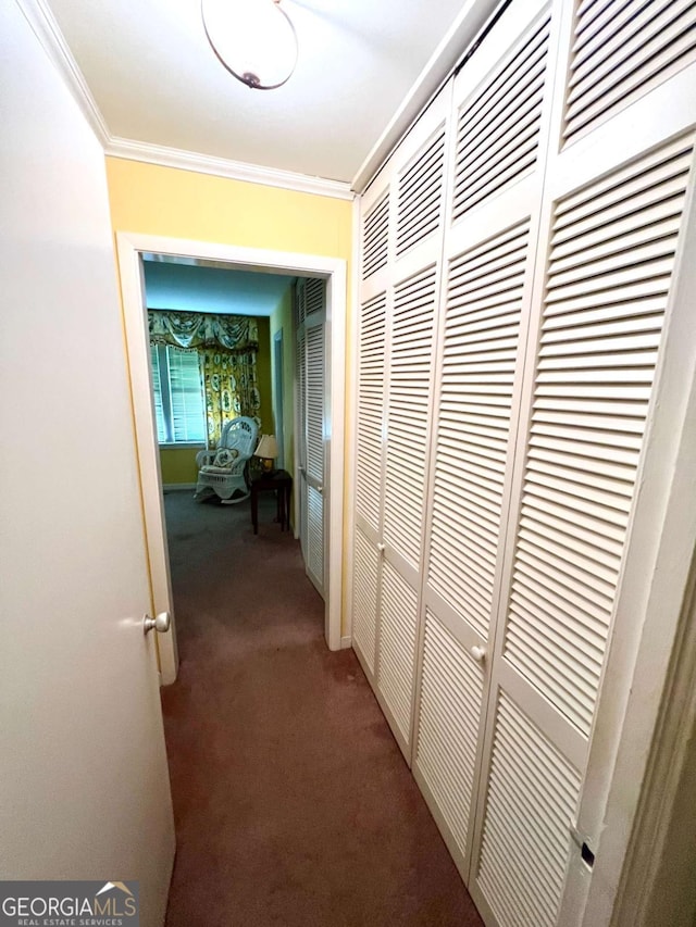 corridor with ornamental molding and dark carpet