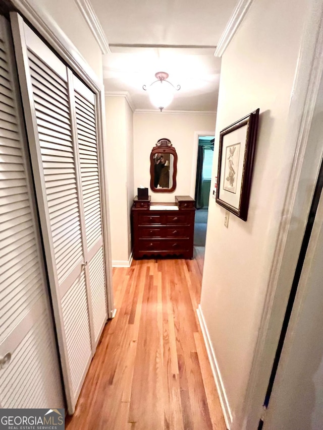 hallway with light wood-type flooring and crown molding