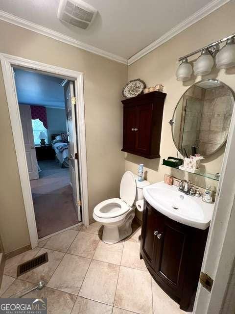 bathroom featuring toilet, ornamental molding, tile patterned floors, and vanity