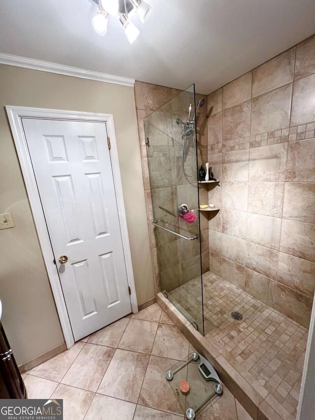 bathroom with crown molding, tile patterned flooring, and a tile shower