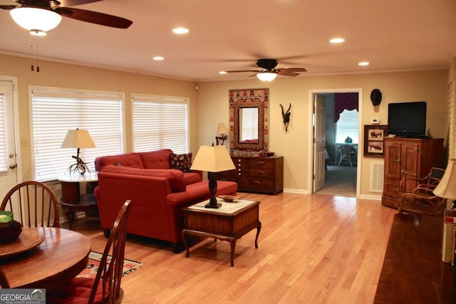 living room featuring light wood-type flooring, ceiling fan, crown molding, and plenty of natural light