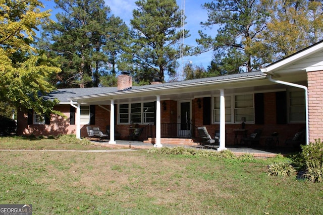 rear view of property featuring a yard and covered porch