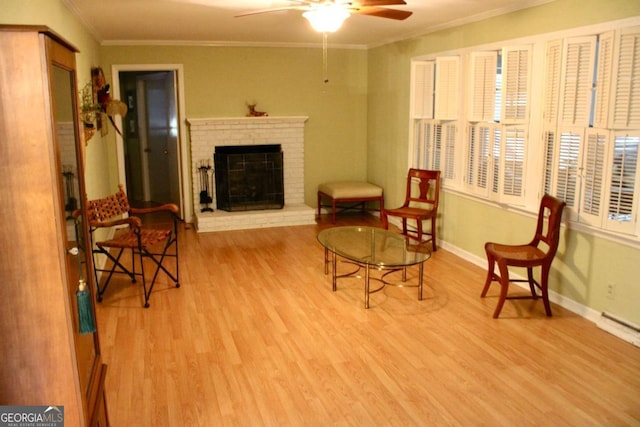 living area with a fireplace, ceiling fan, light hardwood / wood-style flooring, a healthy amount of sunlight, and crown molding