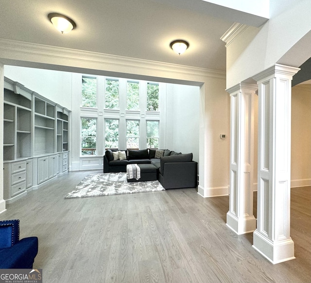 living room featuring built in shelves, ornamental molding, ornate columns, and hardwood / wood-style floors