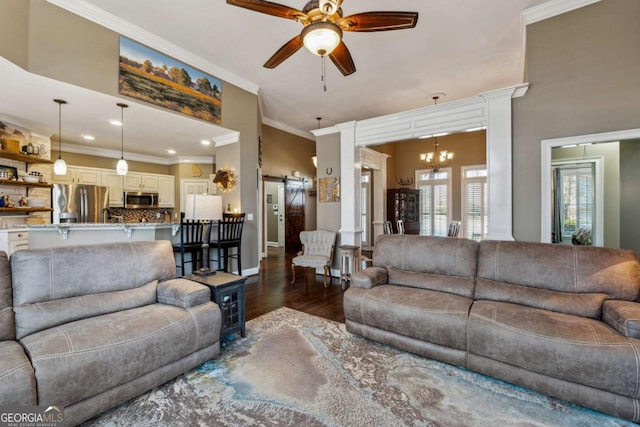 living room with ceiling fan with notable chandelier, a barn door, dark hardwood / wood-style floors, and crown molding