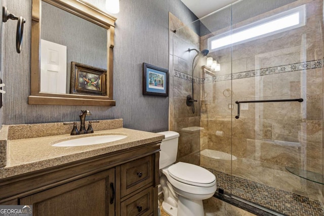 bathroom featuring toilet, a shower with door, and vanity