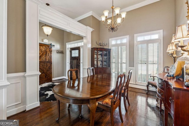 dining room featuring ornamental molding, dark wood-type flooring, a notable chandelier, and a barn door