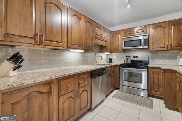 kitchen with light stone counters, appliances with stainless steel finishes, light tile patterned flooring, and sink