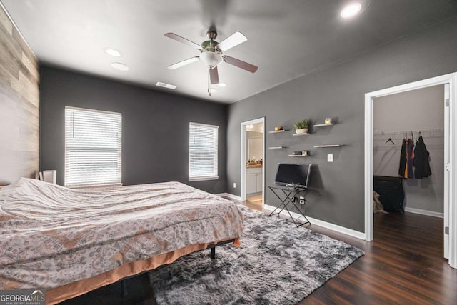 bedroom with dark hardwood / wood-style floors, ensuite bathroom, a closet, a walk in closet, and ceiling fan