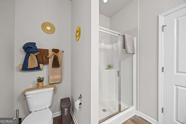 bathroom with toilet, an enclosed shower, and hardwood / wood-style floors