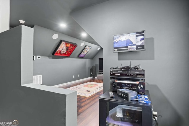 cinema room featuring hardwood / wood-style floors and lofted ceiling