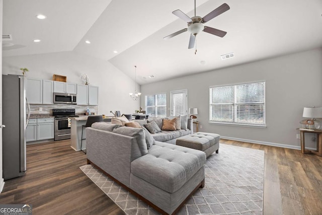 living room featuring dark hardwood / wood-style flooring, vaulted ceiling, and ceiling fan with notable chandelier