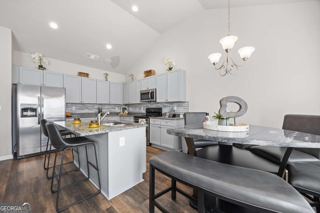 kitchen with sink, tasteful backsplash, a breakfast bar area, light stone countertops, and appliances with stainless steel finishes