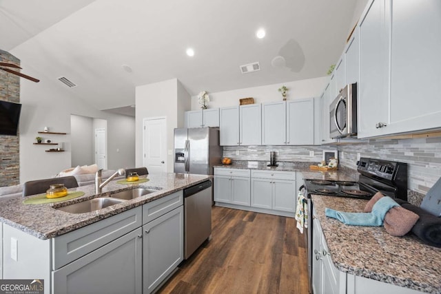 kitchen with a center island with sink, appliances with stainless steel finishes, vaulted ceiling, and sink