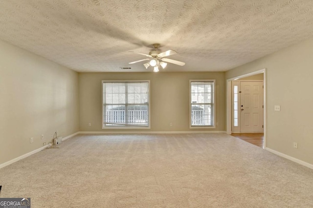 spare room with a textured ceiling, ceiling fan, and light carpet