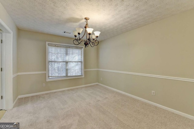 empty room featuring carpet flooring, an inviting chandelier, and a textured ceiling