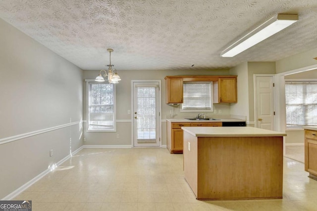 kitchen featuring sink, a textured ceiling, hanging light fixtures, and a notable chandelier