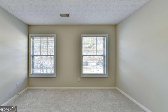 unfurnished room featuring a textured ceiling and light colored carpet